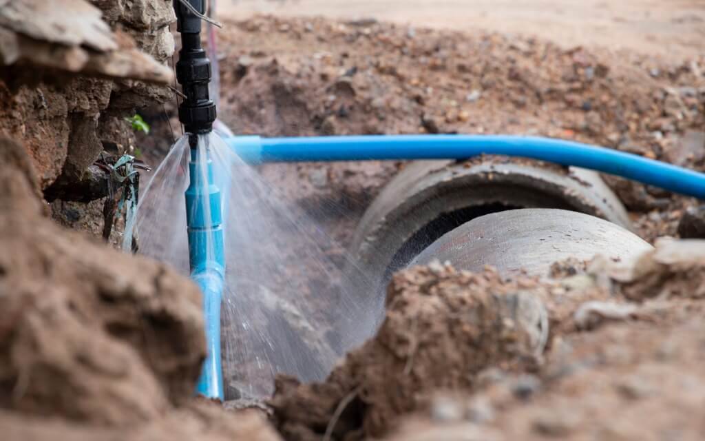 Burst water pipe spraying water into a hole